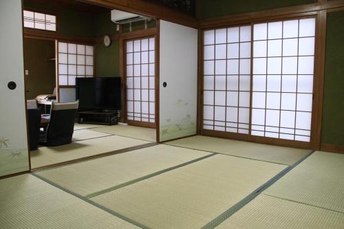 an empty room with glass doors and a television at Vacation rental PIGGY's Nichinan in Nichinan