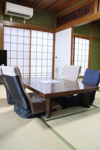 a wooden table with chairs and a laptop on it at Vacation rental PIGGY's Nichinan in Nichinan