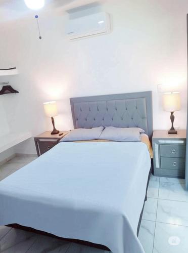a bedroom with a large white bed with two lamps at Departamento El Tesoro - Olas Azules - 3 Min Malecón y Playas in Mazatlán