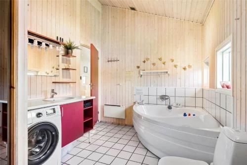 a bathroom with a tub and a washing machine at FY237-Otterup-Vestparken-6 in Otterup