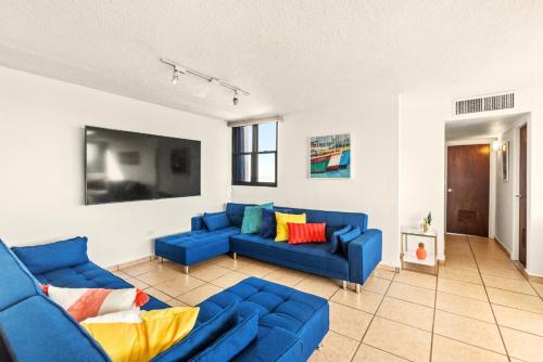 un soggiorno con divani blu e TV di Waterside Flat With Garage And Easy Beach Access a San Juan