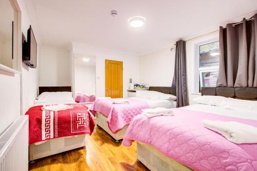 Un dormitorio con tres camas con sábanas rosas. en Amaro Hotel, en Londres