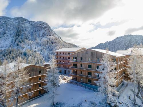 a hotel in the snow with mountains in the background at Sonnenalpe Nassfeld Bergblume in Sonnenalpe Nassfeld