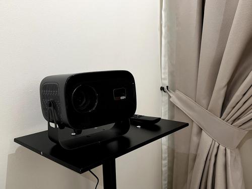 a television sitting on a table next to a curtain at Calm MUJI-Inspired Home - Stunning Sunset View - Steps To IOI City Mall - Your Best Urban Retreat in Putrajaya