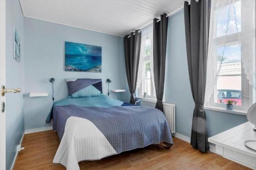 a bedroom with a bed with blue walls and windows at FY245-Assens-Ramsherred-25 in Assens