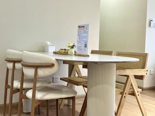a dining room table with chairs and a white table at Calm MUJI-Inspired Home - Stunning Sunset View - Steps To IOI City Mall - Your Best Urban Retreat in Putrajaya