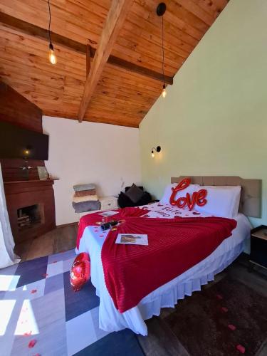 a bedroom with a large bed with a red blanket at Chalés Refúgio no Campo in Santo Antônio do Pinhal