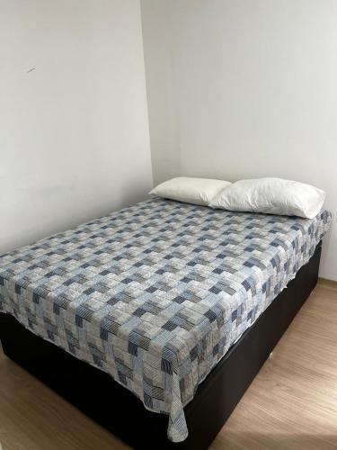 a bed with a checkered blanket and a pillow at SUITE Ponta Negra in Manaus