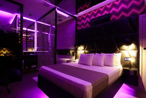 Un dormitorio con una cama con luces moradas. en Savana Motel, en Ribeirão Preto