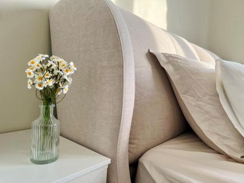 a vase of flowers on a table next to a couch at Calm MUJI-Inspired Home - Stunning Sunset View - Steps To IOI City Mall - Your Best Urban Retreat in Putrajaya