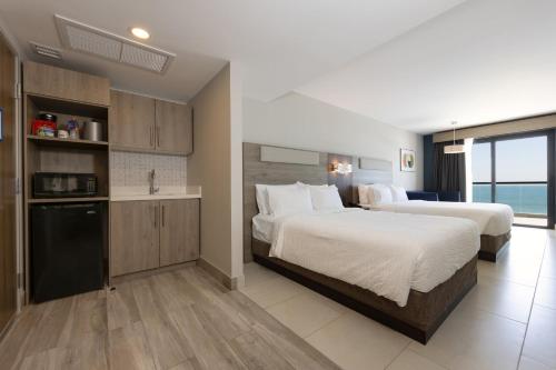 a hotel room with two beds and a kitchen at Holiday Inn Express & Suites Mazatlan by IHG in Mazatlán