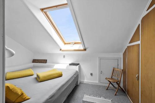 1 dormitorio con 1 cama con ventana y silla en 5599-Gudhjem-Grevens-Dal-2, en Gudhjem