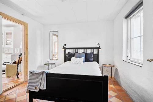 a bedroom with a black bed in a white room at FY252-Haarby-Brunshusevej-23 in Hårby