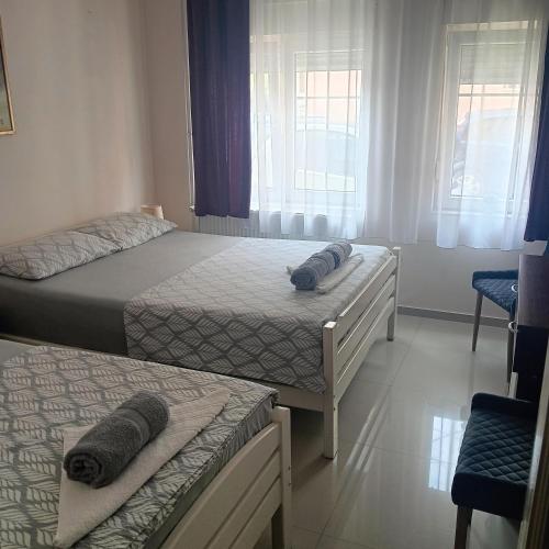 a bedroom with two beds and a chair and windows at Vila Eni in Smederevo