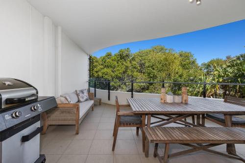 a balcony with a table and a grill at Cotton Beach 97 Luxurious Mid Floor Apartment in Casuarina