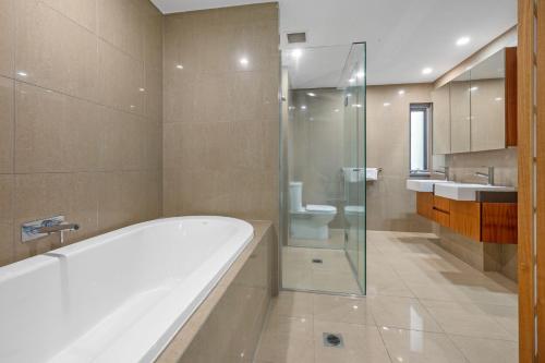 a bathroom with a bath tub and a sink at Cotton Beach 97 Luxurious Mid Floor Apartment in Casuarina