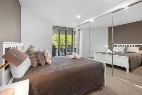 a bedroom with a bed and a large mirror at Cotton Beach 97 Luxurious Mid Floor Apartment in Casuarina