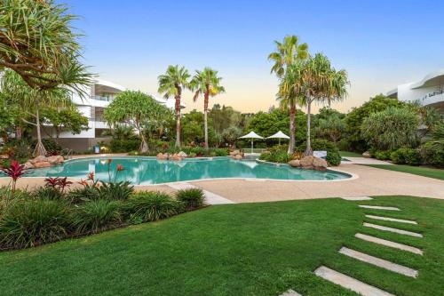 a swimming pool in a resort with palm trees at Cotton Beach Apartment 33 With Pool Views in Casuarina