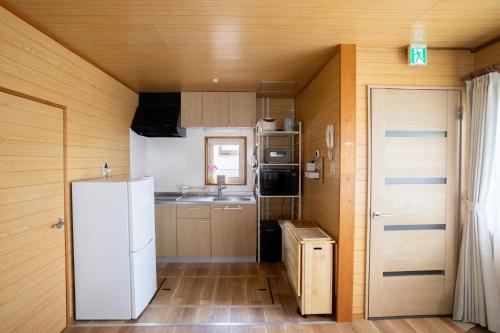 a small kitchen with a white refrigerator in a room at LAKE TOYA PREMIUM CABIN in Lake Toya