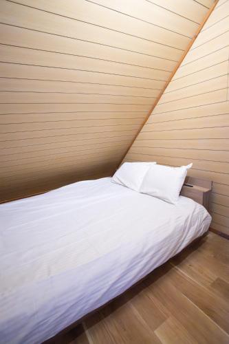 a bed with white sheets and pillows in a room at LAKE TOYA PREMIUM CABIN in Lake Toya