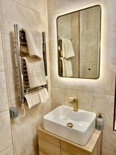 a bathroom with a sink and a mirror and towels at Double Deluxe Centre Apartment- Free Parking - Self Check-In - Cctv in Huddersfield