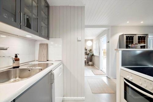 a white kitchen with a sink and a stove at FY377-Nyborg-Svalevej-6 in Nyborg