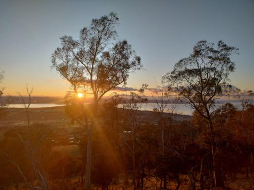 a sunset over a body of water with trees at Mount Rumney Escapes - 3 Seaview Wombat House in Mount Rumney