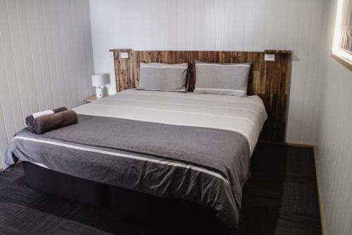 a bedroom with a large bed with a wooden headboard at Mount Rumney Escapes - 3 Seaview Wombat House in Mount Rumney