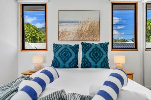 a bedroom with a bed with blue and white pillows at Belle Escapes Sunset Boulevard in Palm Cove
