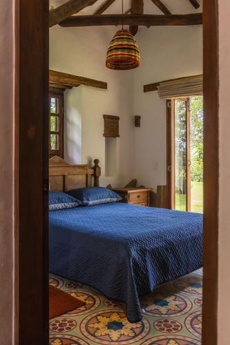 a bedroom with a bed with a blue comforter at Refugio Ecoturístico Villa Clarita in Estación El Salto