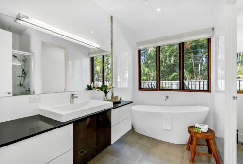 a white bathroom with a tub and a sink at Belle Escapes Sunset Boulevard in Palm Cove