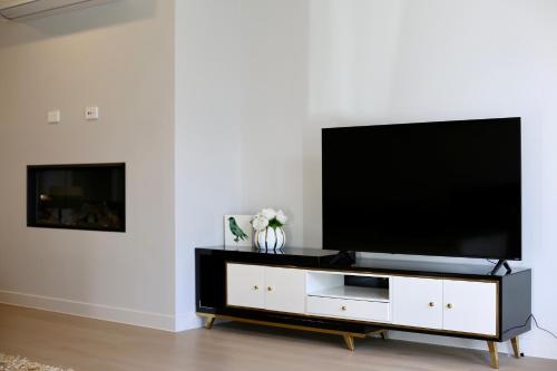 a living room with a flat screen tv on a white entertainment center at Elegant New Luxury Retreat in Remuera in Auckland