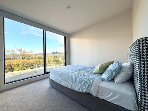 a bedroom with a bed and a large window at Elegant New Luxury Retreat in Remuera in Auckland