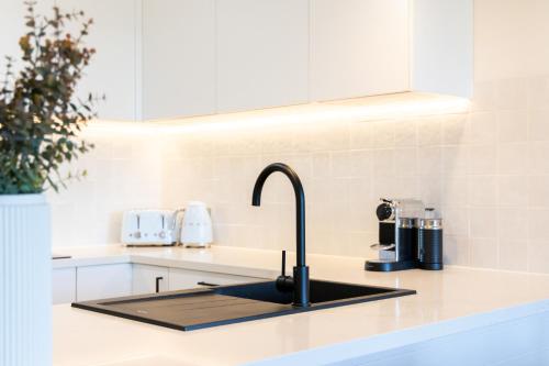 a kitchen sink with a faucet on a counter at Surfrider - Beach front apartment with pool in Byron Bay