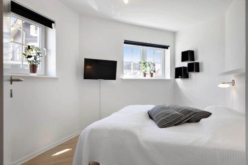 a white bedroom with a bed and a tv on the wall at FY390-Bogense-Vestre-Engvej-118-st-tv in Bogense