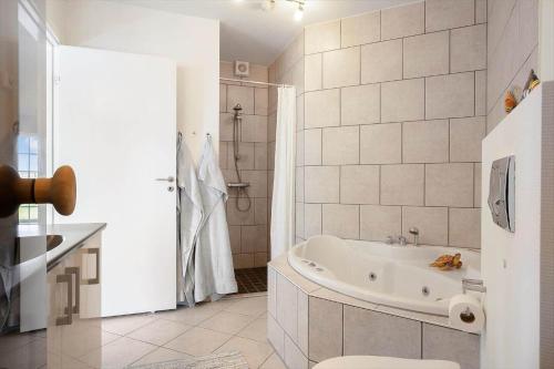 a white bathroom with a tub and a shower at FY390-Bogense-Vestre-Engvej-118-st-tv in Bogense
