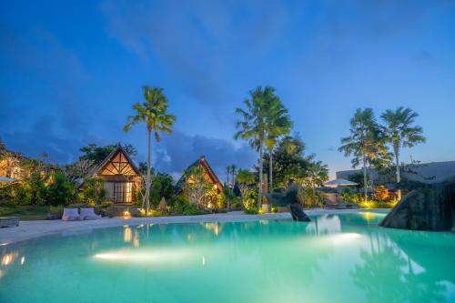 a swimming pool in front of a resort at night at Cemara Hills Uluwatu, The Reserve - Cottages & Villas in Uluwatu