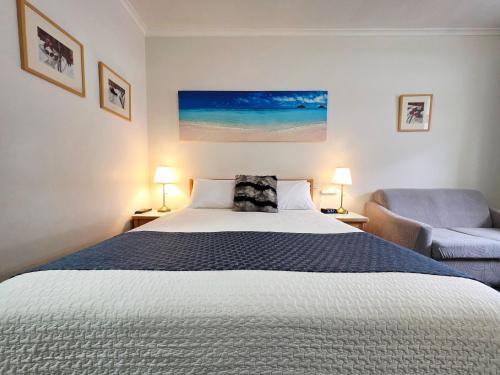 a bedroom with a large bed and a chair at Hi 5 Glenelg Studio Apartment in Glenelg