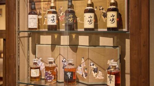 a display of bottles of alcohol on a shelf at Kumonoue Fuji Hotel Premium room - No Mt Fuji view with open-air bath in Fujikawaguchiko