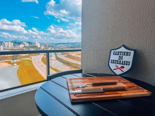 a table with a sign on the wall next to a window at Apto com 1 quarto e sacada com churrasqueira in Brusque