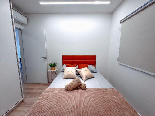 a bedroom with a large bed with a red headboard at Apto com 1 quarto e sacada com churrasqueira in Brusque