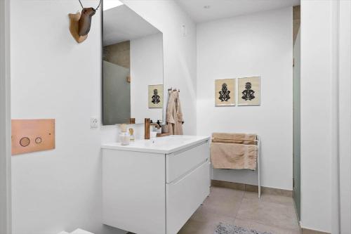 a white bathroom with a sink and a mirror at 5607-Svaneke-Mollebakken-8-P in Svaneke