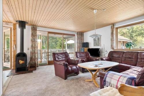 a living room with leather furniture and a wood stove at 2715-Nexo-Munkegardsskoven-32 in Neksø