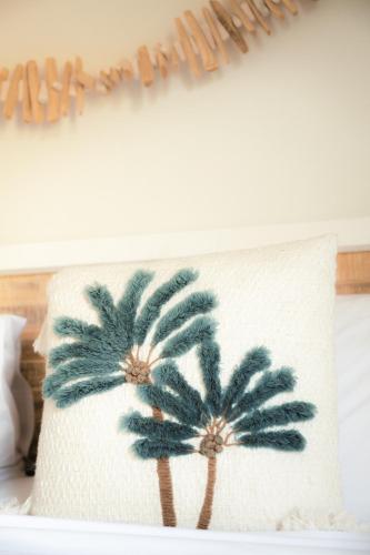 a pillow with palm trees on a bed at Melo Beach Escape - Luxury Gnarabup beach house in Gnarabup
