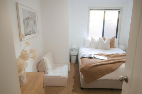 a bedroom with a bed and a chair and a window at Melo Beach Escape - Luxury Gnarabup beach house in Gnarabup
