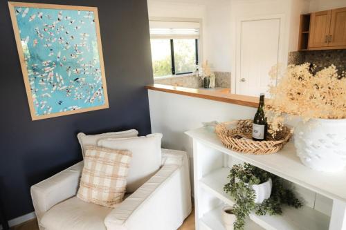 a living room with a white chair and a painting at Melo Beach Escape - Luxury Gnarabup beach house in Gnarabup