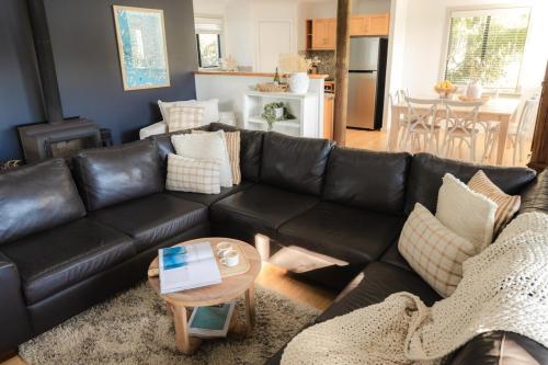 a living room with a black leather couch and a table at Melo Beach Escape - Luxury Gnarabup beach house in Gnarabup