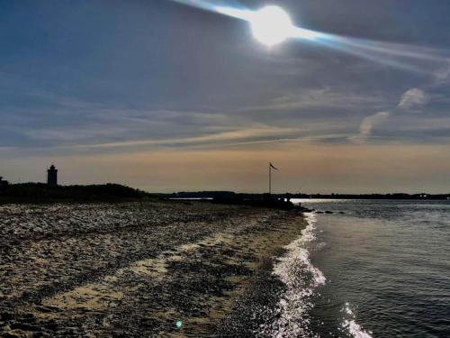 a beach with a lighthouse and the sun in the sky at Middelfart Holiday Center in Middelfart