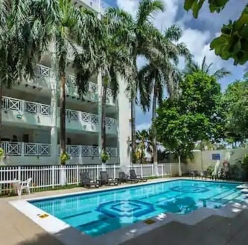 a pool in front of a hotel with palm trees at Apartaamento en San Andres frente al mar con balcon in San Andrés