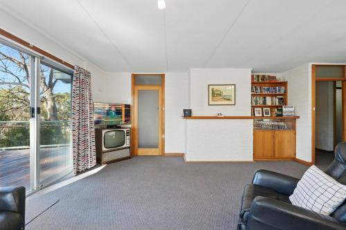 a living room with a couch and a tv at Coningham Beach House - 3 Bedrooms in Coningham